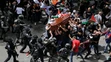 Izraelskí vojaci a policajti zasahujú proti nahnevanému davu na pohrebe novinára televízie Al Jazeera.