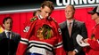 Connor Bedard si oblieka dres Chicaga na NHL drafte 2023.