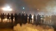 Príslušníci polície kráčajú v hustom dyme pošas rasovo motivovanej demonštrácie v americkom meste Ferguson.