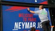 Zamestnanec pripevňuje uvítací transparent pre Brazílčana Neymara pred oficiálnym klubovým obchodom Paríža Saint-Germain.