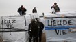 Migranti v tábore pri Calais protestujú na strechách búd.