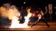 Demonštrant hádže  na policajtov zápalnú fľašu počas rasovo motivovaného protestu v americkom meste Ferguson.