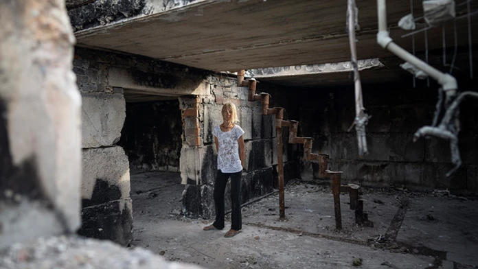Hanna Dynaeva stojí vo svojom dome, ktorý bol zničený ruským bombardovaním v dedine Novoselivka.