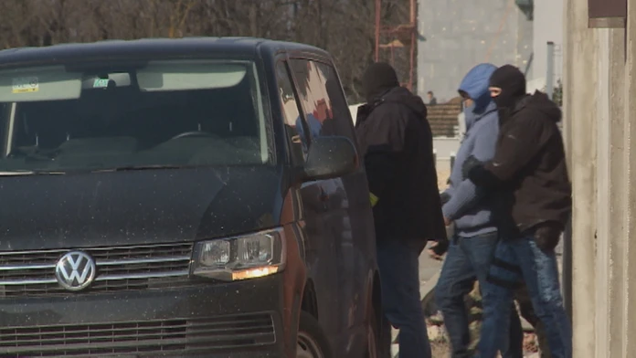 Policajti prevážajú mužov, zadržaných počas razií.