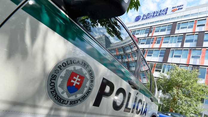 Policajné auto stojí počas razie pred budovou spoločnosti Slovenské elektrárne.