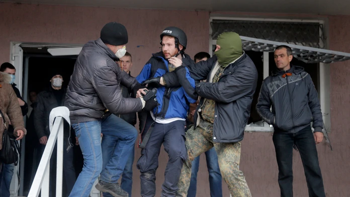 Maskovaní proruskí aktivisti útočia na britského fotografa Fredericka Paxtona počas útoku na policajnú stanicu v ukrajinskom mes
