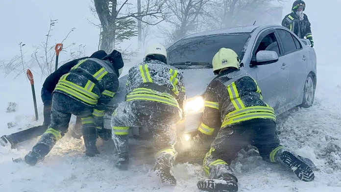 Ukrajinskí záchranári snažia odtlačiť auto, ktoré uviazlo na ceste počas snehovej víchrice v Odeskej oblasti.