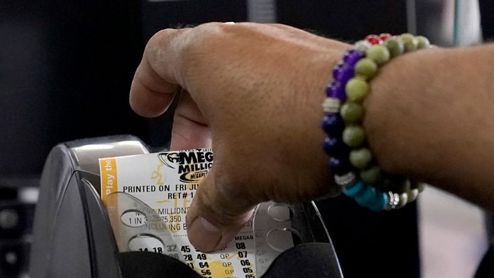 Zamestnanec samoobsluhy vyťahuje zákazníkovi tiket americkej lotérie Mega Millions v texaskom Richardsone.