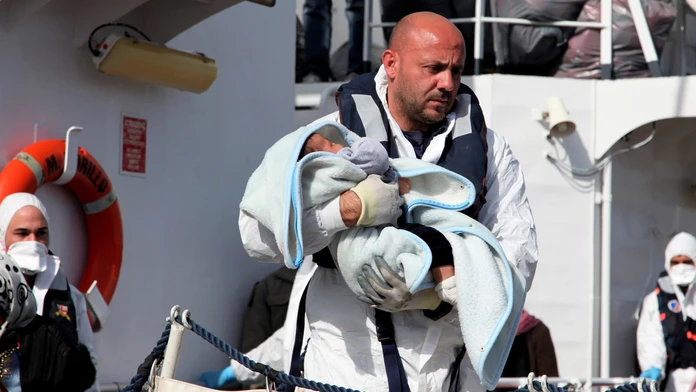 Záchranár nesie dieťa po príchode lode talianskej pobrežnej stráže s migrantami.