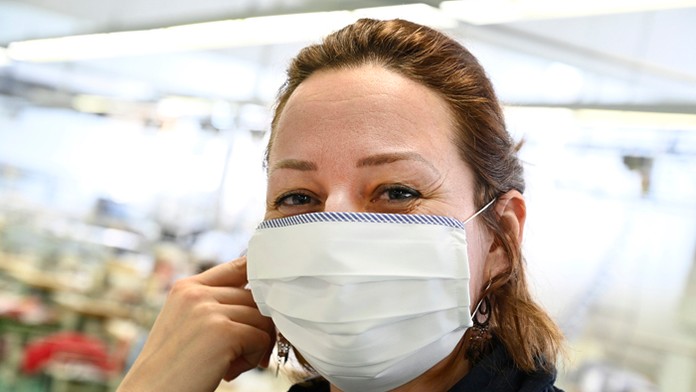 Pracovníčka  textilnej fabrike v Bánovciach nad Bebravou šije ochrannú rúšku.