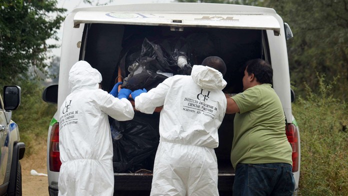 Na archívnej snímke forenzní experti nakladajú do vozidla mŕtve telo.