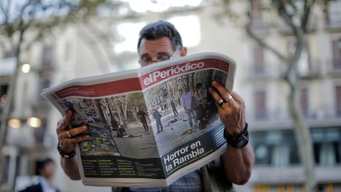 Muž číta španielske noviny s titulkami o teroristickom útoku v Barcelone.