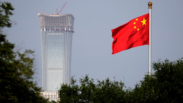 Čínska národná vlajka veje vedľa rozostavaného mrakodrapu China Zun v Pekingu. 