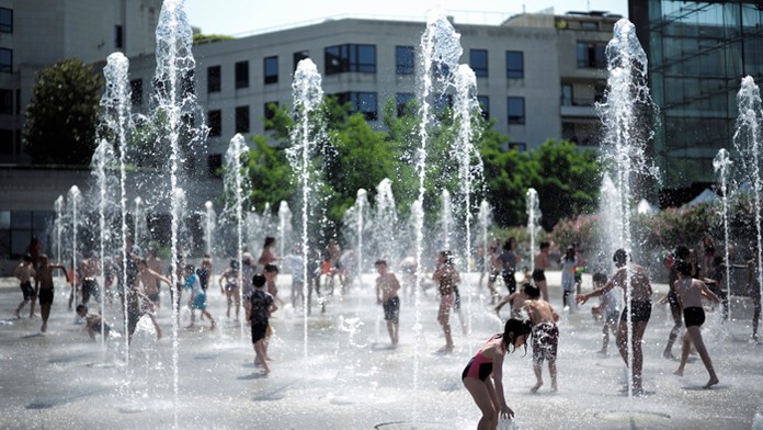 Deti sa hrajú vo fontáne počas slnečného a teplého počasia v parku v Paríži.