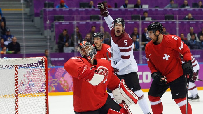 Lotyšský útočník Janis Sprukts reaguje po tom, ako sa puk ocitá v sieti švajčiarskeho gólmana Jonasa Hillera 