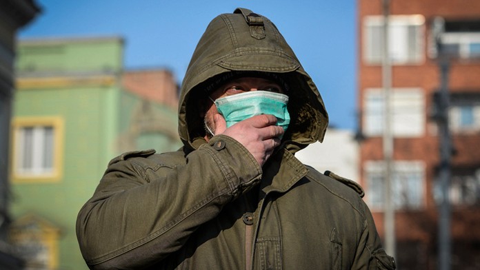 Chodec si v smogu zakrýva tvár maskou.