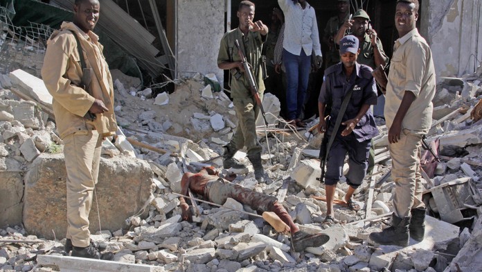 Členovia bezpečnostných jednotiek stoja vedľa mŕtveho tela po bombovom útoku na hotel Ambassador