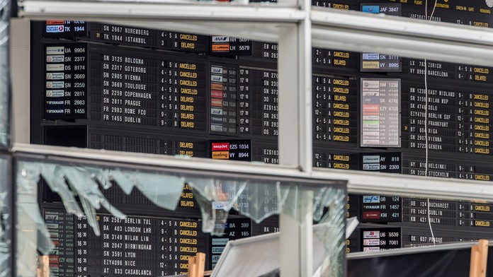 Pohľad cez rozbité okno na tabuľu odletov po teroristickom výbuchu na letisku Zaventem 23. marca.
