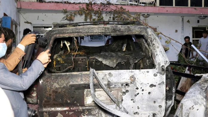 Afganskí novinári si fotia zničené auto v dome po útoku americkej armády dronom na teroristickú organizáciu Islamský štát v Kábu