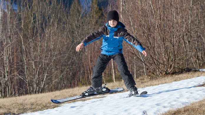 Chlapec na lyžiach po tráve