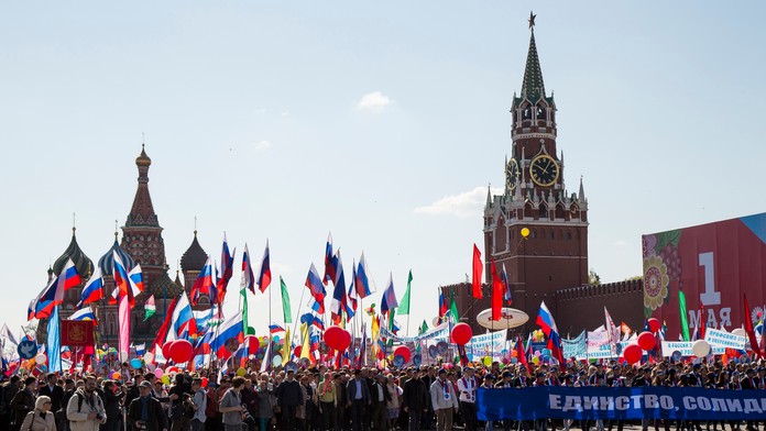 Rusi mávajú zástavami a skandujú počas prvomájových osláv na Červenom námestí v Moskve.