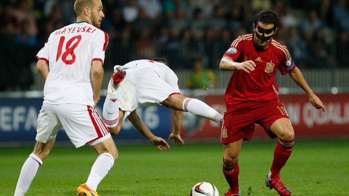 Bielrusi Ivan Maevski (vľavo) a Sergej Kisljak v akcii so španielskym stredopoliarom Cescom Fábregasom.