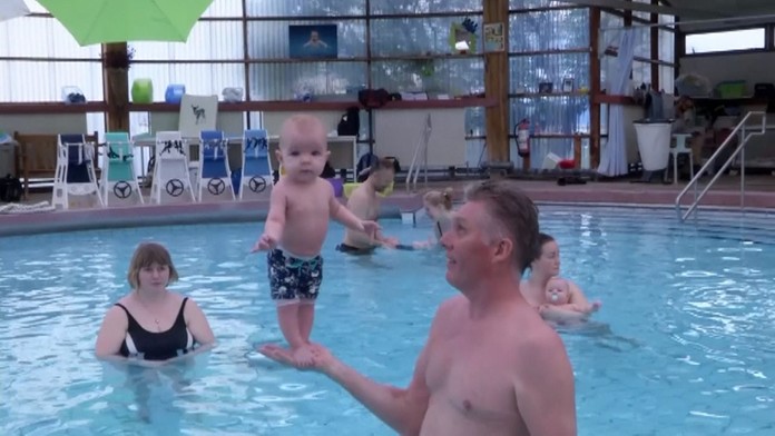 Trojmesačné bábätko stojí terapeutovi na rukách.