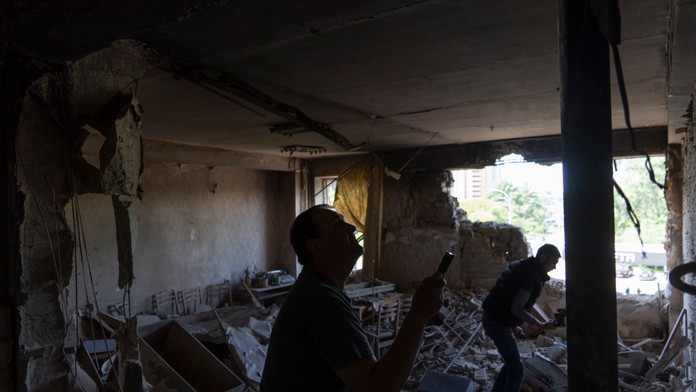 Muži kontrolujú svoju kanceláriu, ktorú zasiahol dron počas nočného útoku ruskej armády v Kyjeve.