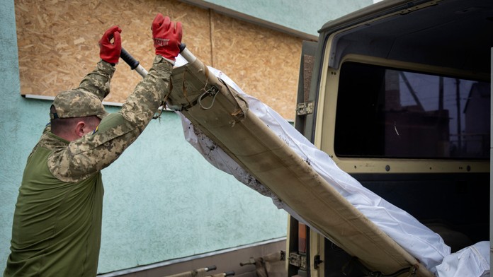 Vojak nakladá do dodávky telo ukrajinského vojaka.