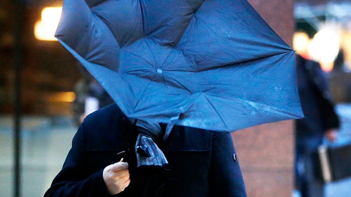 Na snímke muž s vyvráteným dáždnikom v prudkom vetre.