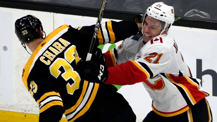 Jaroslav Halák z Bostonu chytá puk pred Michaelom Frolíkom z Calgary.