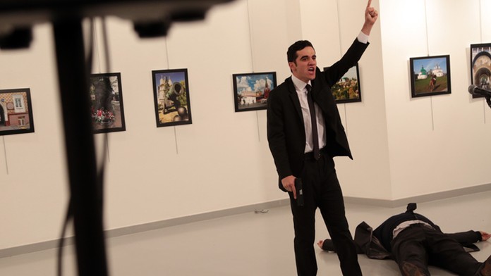 Muž gestikuluje vedľa tela postreleného ruského veľvyslanca.