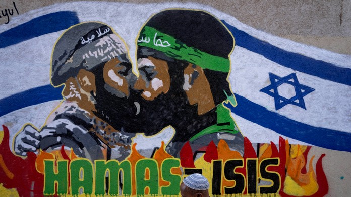 Muž kráča okolo grafitu s nápisom Hamas rovná sa Islamský štát v Tel Avive.