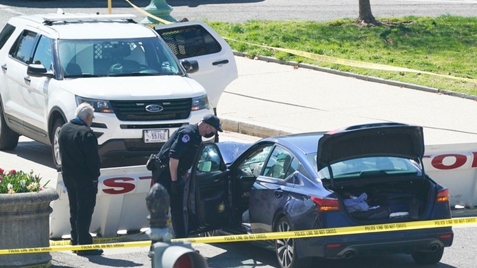 Policajti stoja neďaleko automobilu, ktorý narazil do bariéry pred sídlom vlády USA.