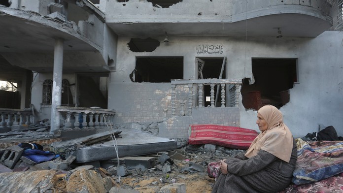 Palestínska žena sedí pri domoch zničených pri izraelskom bombardovaní v pásme Gazy.