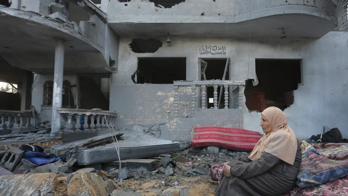 Palestínska žena sedí pri domoch zničených pri izraelskom bombardovaní v pásme Gazy.