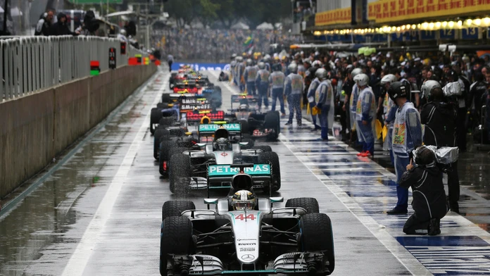 Lewis Hamilton stojí na čele monopostov v boxovej uličke počas prerušenia preteku pre nehodou Kimiho Räikkönnena.