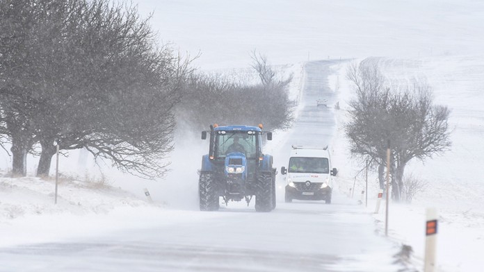 Traktor a dodávka na ceste III. triedy zafúkanej snehovými jazykmi medzi Huncovcami a Vrbovom. 