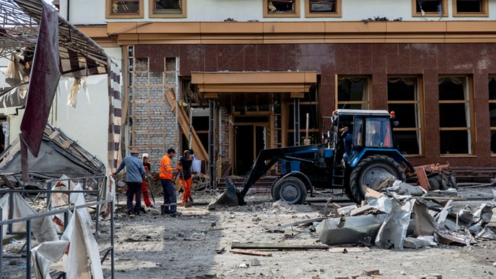 Pracovníci odpratávajú trosky zničeného hotela v centrálnom parku v ukrajinskom Záporoží.