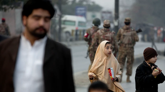 Rodinný príslušník odvádza deti mimo školy, na ktorú v pakistanskom Pešaváre zaútočil Taliban. 16. decembra 