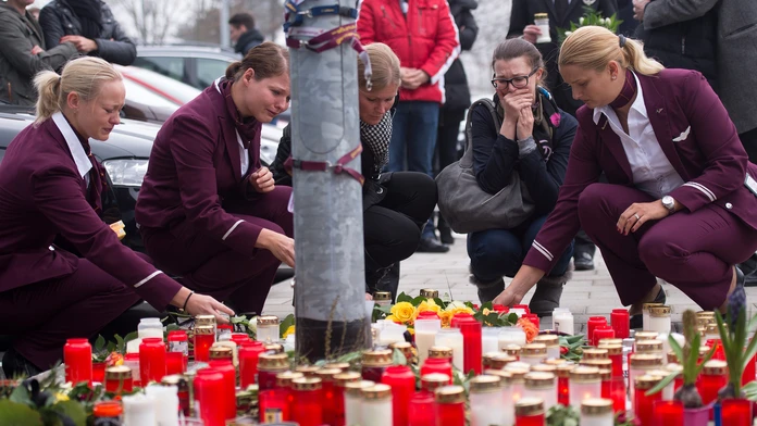 Zamestnankyne nemeckej spoločnosti Germanwings kladú sviečky a kvety  pred sídlom leteckej spoločnosti Germanwings.