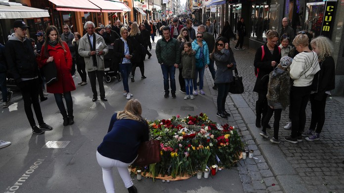 Žena kladie kvety na rušnej pešej zóne Drottninggatan v centre Štokholmu
