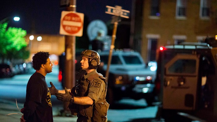 Policajt a zadržaný muž po výtržnostiach v Baltimore po zákaze vychádzania. 29. apríla