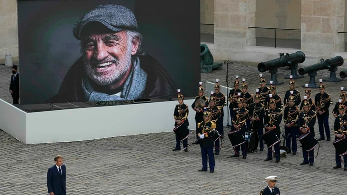 Prezident E. Macron prechádza okolo portrétu Jeana-Paula Belmonda po pietnej rozlúčke.