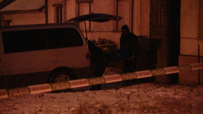 Pohrebná služba vynáša mužove telo z domu.