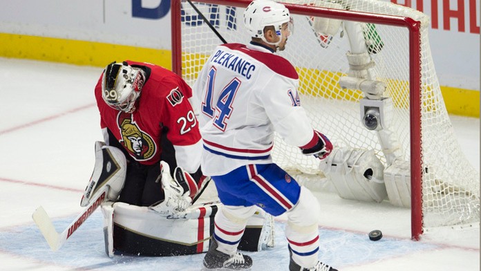 Hokejista Montrealu Canadiens Čech Tomáš Plekanec prekonáva brankára Ottawy Senators Matta O'Connora v zápase zámorskej hokejove