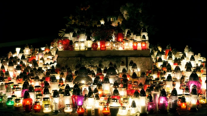 Na snímke je hrob, na ktorom horí množstvo sviečok. Je noc a je tma. 