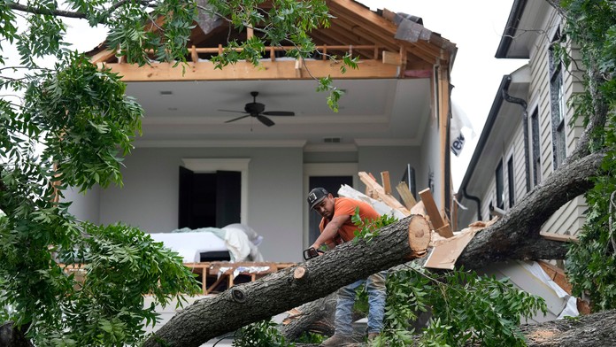 Muž pomocou motorovej píly rozrezal strom, ktorý odtrhol fasádu domu v Houstone po ničivých búrkach.