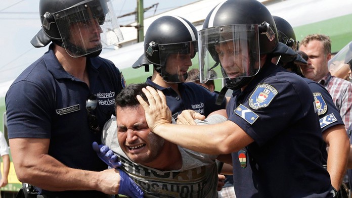 Na snímke policajti zatýkajú migranta, ktorý pricestoval vlakom z Budapešti na železničnej stanici v maďarskom meste Bicske.