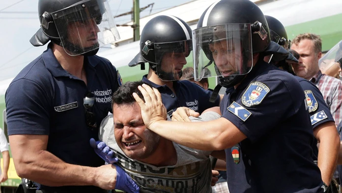 Na snímke policajti zatýkajú migranta, ktorý pricestoval vlakom z Budapešti na železničnej stanici v maďarskom meste Bicske.
